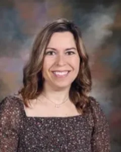 A woman in brown shirt smiling for the camera.